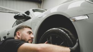 O que reprova na vistoria veicular? Mecânico examinando o pneu do carro para saber o que reprova na vistoria veicular