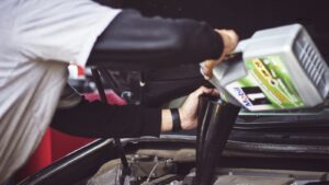 Homem colocando óleo de motor no carro, troca de óleo