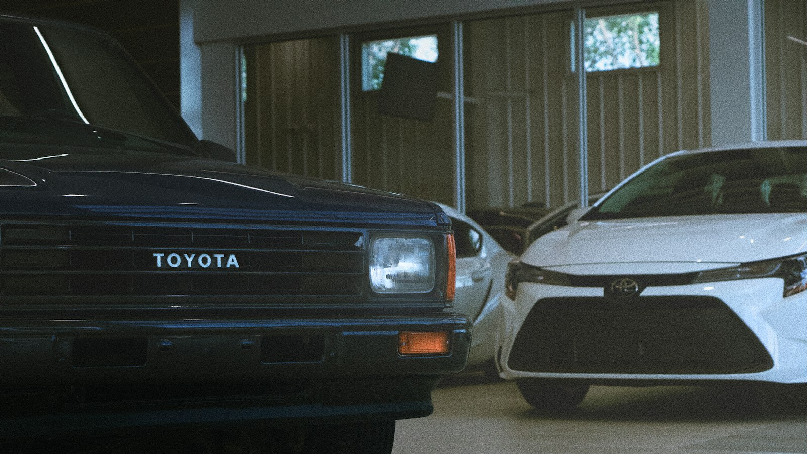Picape Toyota antiga ao lado de sedã moderno, desvalorização de carros