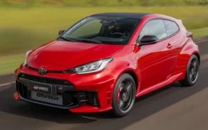 Toyota GR Yaris 2026: preço de R$ 354.990 e chegada Toyota GR Yaris 2026 vermelho em movimento, vista frontal 3/4 em pista com teto preto