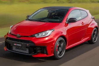 Toyota GR Yaris 2026 vermelho em movimento, vista frontal 3/4 em pista com teto preto