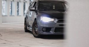 Mitsubishi Lancer sedã cinza vista frontal com faróis acesos