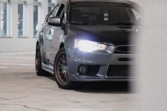 Mitsubishi Lancer sedã cinza vista frontal com faróis acesos