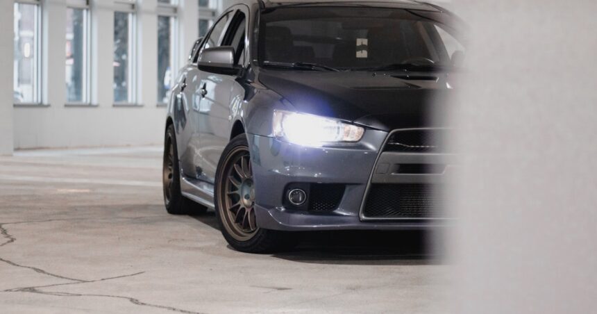 Mitsubishi Lancer sedã cinza vista frontal com faróis acesos