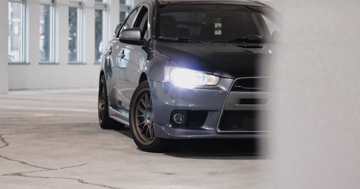 Mitsubishi Lancer sedã cinza vista frontal com faróis acesos