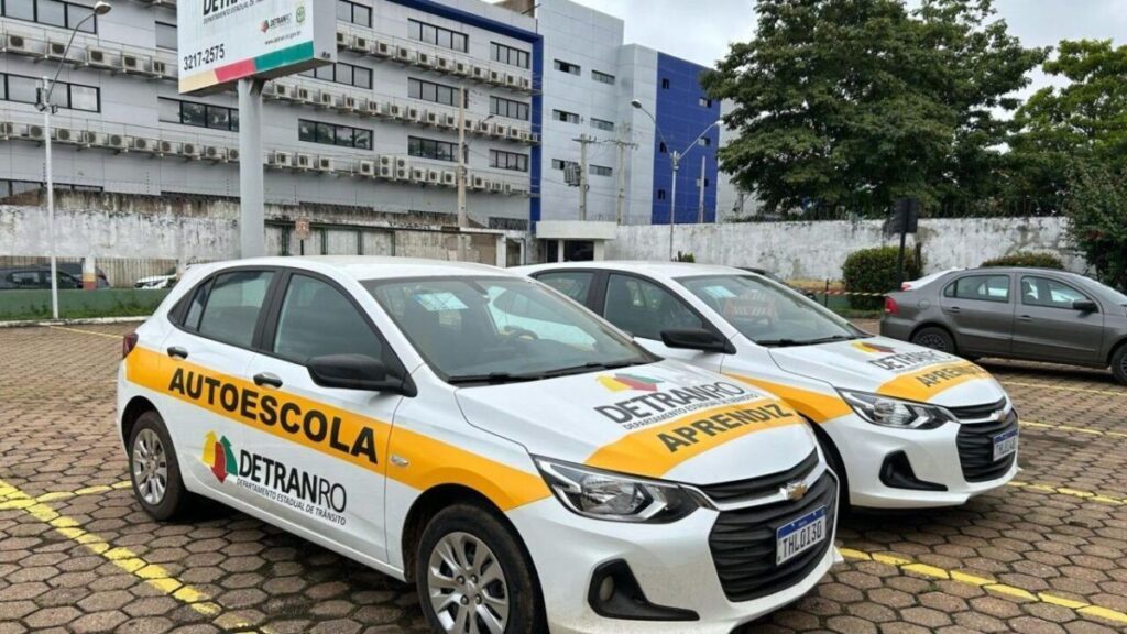 Carros de autoescola do Detran estacionados com adesivos de identificação