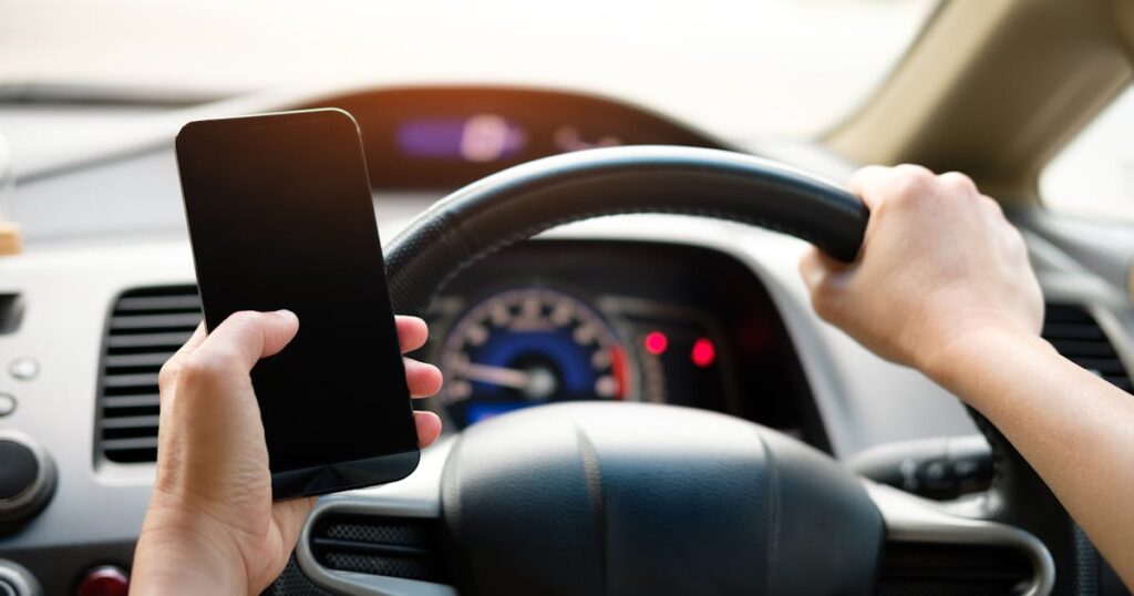 Motorista segurando smartphone no volante do carro para acessar CRLV digital