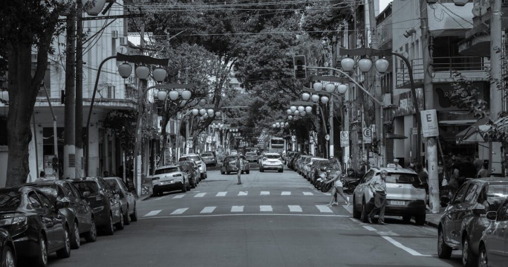 Rua com carros estacionados em cidade brasileira, trânsito urbano