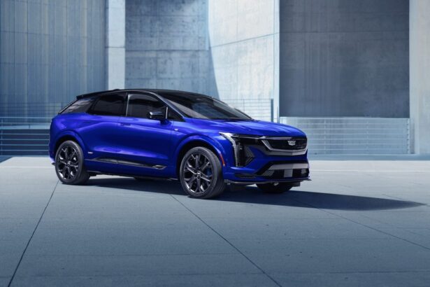 Cadillac Optiq AWD 2026 azul-metálico, vista frontal 3/4 em estúdio, com assinatura luminosa da grade e rodas grandes