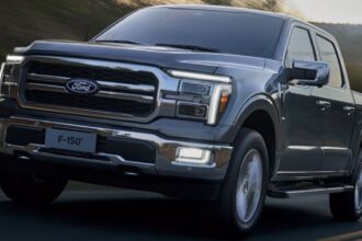 Ford F-150 branca rebocando trailer em vista traseira 3/4, destacando o engate e as luzes do reboque