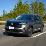 Nissan Kicks 220T Sense 2026 prata, vista frontal 3/4 em cenário urbano, destaque para grade dianteira e faróis