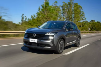 Nissan Kicks 220T Sense 2026 prata, vista frontal 3/4 em cenário urbano, destaque para grade dianteira e faróis