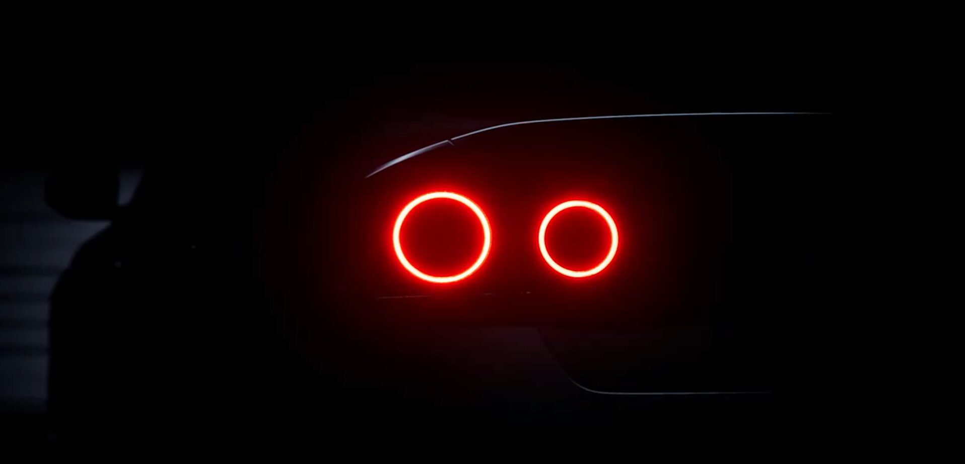 montagem comparativa horizontal entre o teaser frontal do Nissan Skyline e um Nissan Skyline R34 clássico, destacando a inspiração visual, landscape