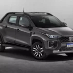 Fiat Strada 2026 branca, vista frontal 3/4 em rua urbana, com foco na grade e nos faróis