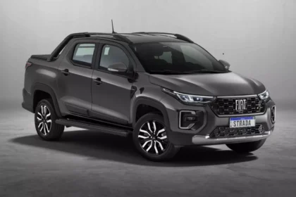 Fiat Strada 2026 branca, vista frontal 3/4 em rua urbana, com foco na grade e nos faróis