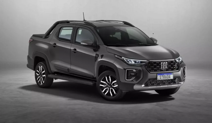 Fiat Strada 2026 branca, vista frontal 3/4 em rua urbana, com foco na grade e nos faróis