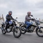 Honda Pop 110i 2026 vermelha, vista frontal 3/4 em ambiente urbano