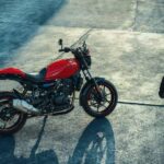 Royal Enfield Guerrilla 450 Apex vermelha, vista frontal 3/4 em estúdio, destacando farol redondo, guidão e pneus esportivos