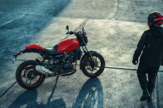 Royal Enfield Guerrilla 450 Apex vermelha, vista frontal 3/4 em estúdio, destacando farol redondo, guidão e pneus esportivos