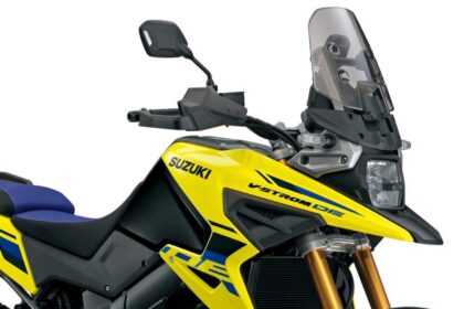 Suzuki V-Strom 1050XT 2027 em estúdio, vista frontal 3/4, cor nova da linha 2027, farol duplo ligado