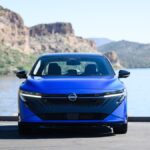 Nissan Sentra 2026 prata, vista frontal 3/4 em ambiente urbano, destaque para faróis de LED e grade dianteira