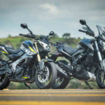 Bajaj Dominar 400 azul escura em vista frontal 3/4, em estúdio, destacando bolha, protetores de mão e postura de sport tourer