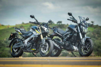 Bajaj Dominar 400 azul escura em vista frontal 3/4, em estúdio, destacando bolha, protetores de mão e postura de sport tourer