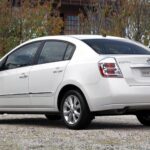 Nissan March 1.0 branco, vista frontal 3/4 em rua urbana, com foco no porte compacto