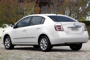 4 Nissan usados baratos: Qual faz mais sentido? Nissan March 1.0 branco, vista frontal 3/4 em rua urbana, com foco no porte compacto