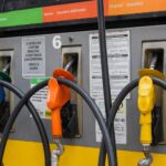 bomba de combustível com gasolina aditivada em posto urbano, destaque para bico de abastecimento e preço na placa