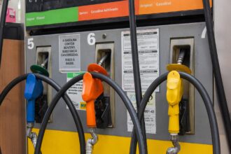 bomba de combustível com gasolina aditivada em posto urbano, destaque para bico de abastecimento e preço na placa