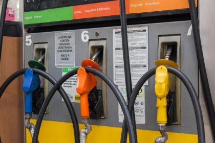 bomba de combustível com gasolina aditivada em posto urbano, destaque para bico de abastecimento e preço na placa