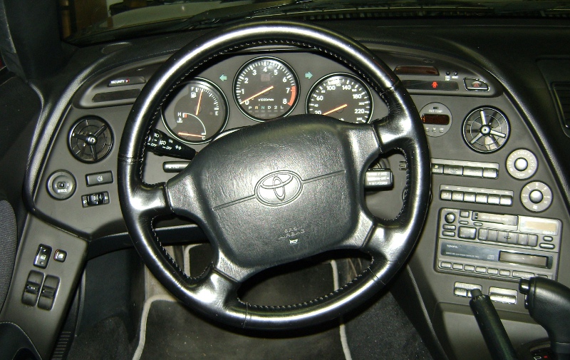 Interior cockpit do Toyota Supra MK4 com painel analógico e volante esportivo