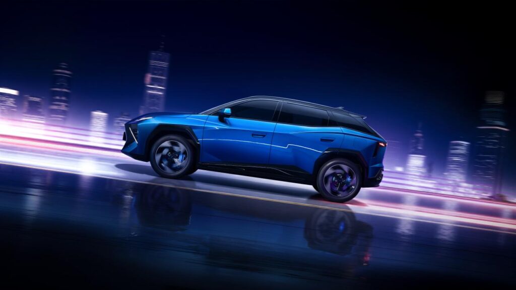 Omoda 4 azul em vista lateral pura em movimento com rastros de luz urbana ao fundo