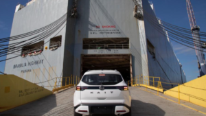 Nissan Kait produzido em Resende, foto frontal horizontal em pátio industrial com caminhões-cegonha ao fundo