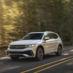 Volkswagen Tiguan prata visto de frente em estacionamento externo, destaque para interior com bancos dianteiros, foto horizontal