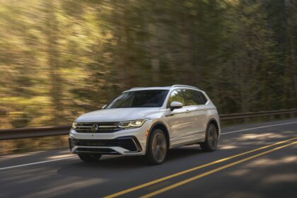 Volkswagen Tiguan prata visto de frente em estacionamento externo, destaque para interior com bancos dianteiros, foto horizontal