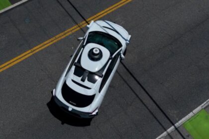 Jaguar I-PACE da Waymo com sensores no teto parado em rua sem saída residencial, vista frontal ampla, horizontal