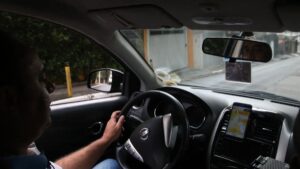 Fila de carros compactos usados por motoristas de aplicativo em grande cidade brasileira, foto frontal horizontal