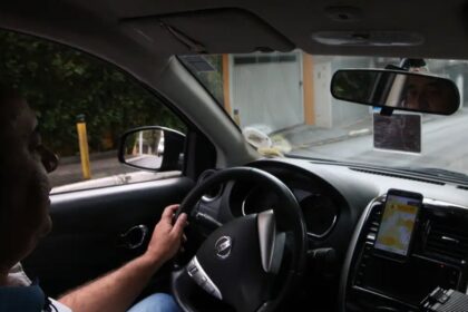 Fila de carros compactos usados por motoristas de aplicativo em grande cidade brasileira, foto frontal horizontal