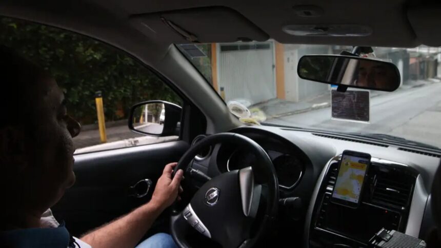 Fila de carros compactos usados por motoristas de aplicativo em grande cidade brasileira, foto frontal horizontal