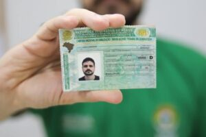 1ª CNH com toxicológico? Veja quando o exame é cobrado balcão de atendimento de Detran com candidato jovem entregando documentos para emissão da Permissão para Dirigir, ambiente interno, foto horizontal