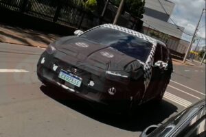 Hyundai i20 de perfil em pista urbana, destacando altura do solo, molduras plásticas e proporções entre HB20 e Creta, landscape