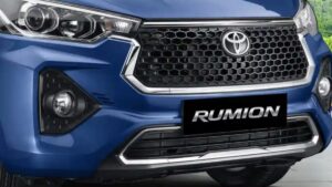 Toyota Rumion prata em foto frontal de três quartos, estacionada em rua urbana, imagem horizontal