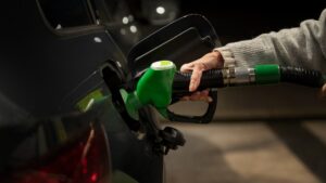 Frentista abastecendo carro flex em posto brasileiro, detalhe da bomba de gasolina comum com visor de preço, foto horizontal
