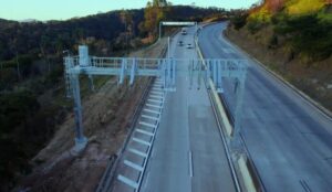Pedágio eletrônico: A multa cai sozinha? Não, e são 5 pontos pórtico de pedágio eletrônico free flow em rodovia brasileira, vista horizontal com carros passando sem praça física