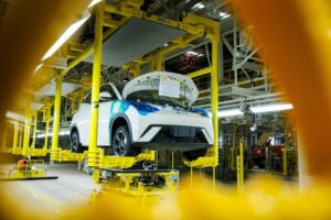 linha de montagem de carro elétrico em fábrica brasileira, com robôs e carroceria em produção, foto horizontal