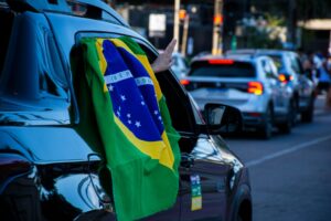 carro de passeio verde e amarelo com pequena bandeira do Brasil presa de forma discreta na lataria, foto lateral em rua urbana, landscape