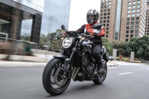 Honda CB 650R E-Clutch 2027 na cor Victory Red, foto frontal três quartos em avenida urbana, landscape