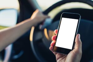 Celular ao volante: Multas disparam em São Paulo e Goiânia Agente de trânsito fiscalizando motoristas em avenida urbana com carros parados no semáforo, um condutor segurando celular, foto horizontal